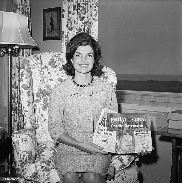 Jacqueline Kennedy holds up a newspaper with a picture of her husband during the 1960 presidential election.