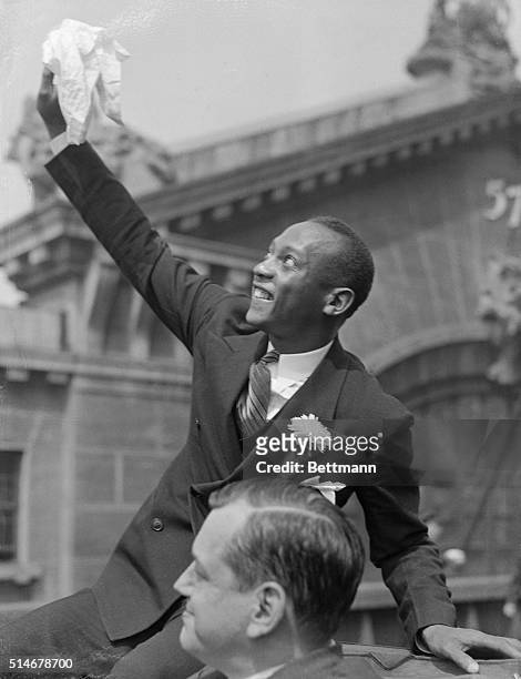 Jesse Owens, sensational track star of the Olympic games, waving to crowds during the "ticker-tape" parade up Manhattan in honor of the Olympic...