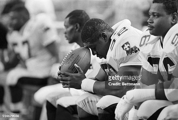 New Orleans Saints linebacker James Haynes rests his head on a football as he sits on the sidelines during the final moments of a losing effort...