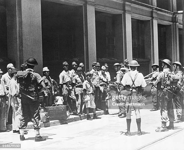 China: ROUND UP TIME IN HONG KONG. Dejected Japanese soldiers face business end of tommy guns held by British troops after round up in dockyard area...