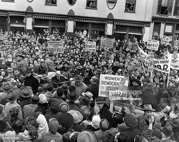 Crowds of political supporters and onlookers surround the campaigning President Roosevelt. Accompanying the President is Treasury Secretary Henry...