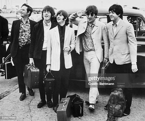 Portrait of The Beatles with their manager, Brian Epstein, arriving in London where they are welcomed by a crowd of two hundred fans.