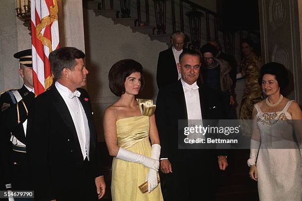 President Kennedy stands with Jacqueline Kennedy, Lyndon Johnson, and Lady Bird Johnson stand together at the White House at a dinner.