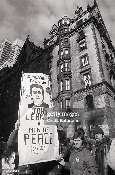 Fans, carrying a memorial banner, gather in front of the Dakota apartment building where John Lennon was murdered.