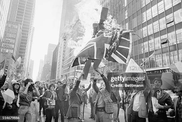 Standing in front of the British consulate, demonstrators burn British Prime Minister in effigy along with a British flag in response to the...