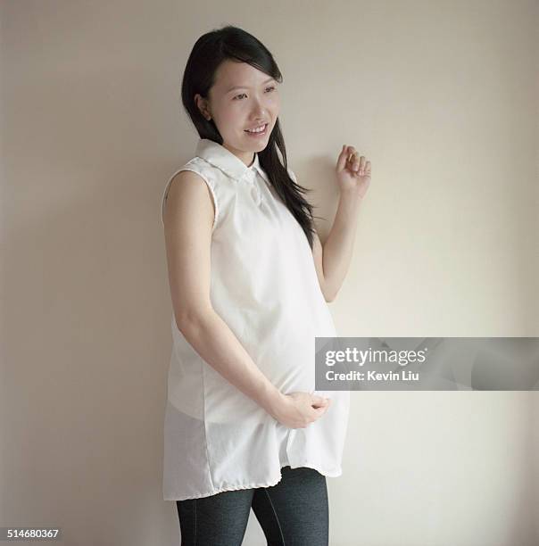 smiling pregnant woman holding her belly - jeggings stock pictures, royalty-free photos & images