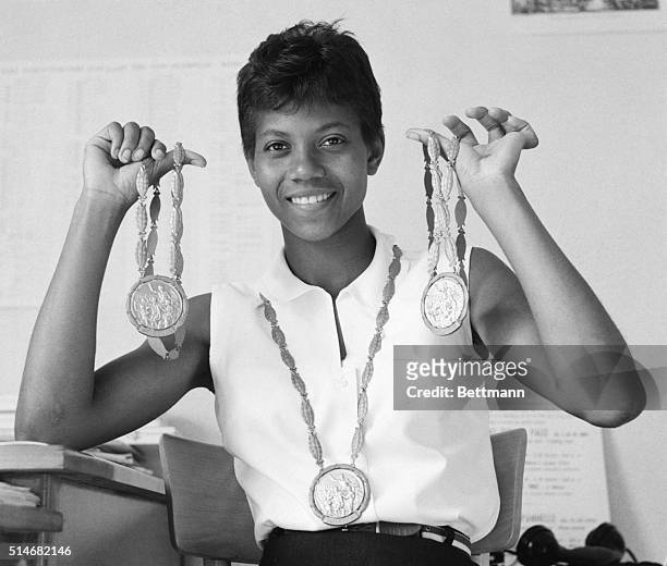 Sprinter Wilma Rudolph wears one gold medal and holds up the two others she won at the 1960 Olympics in Rome.