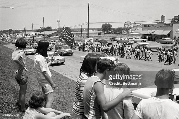 Group of white youths watch and wave confederate flags as a group of Freedom Marchers walks through Senatobia, Mississippi on the fifth day of the...