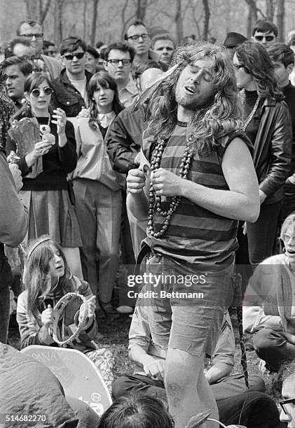 Hippie guy sings and plays his tiny cymbals for a crowd at Detroit's first love-in at Belle Isle Park in 1967.