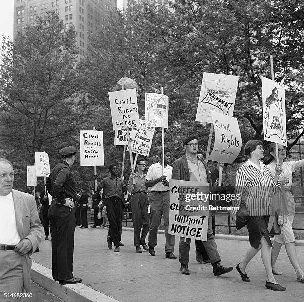 Police officer watches a line of people holding placards in front of City Hall protesting the closure of Greenwich Village coffee shops.