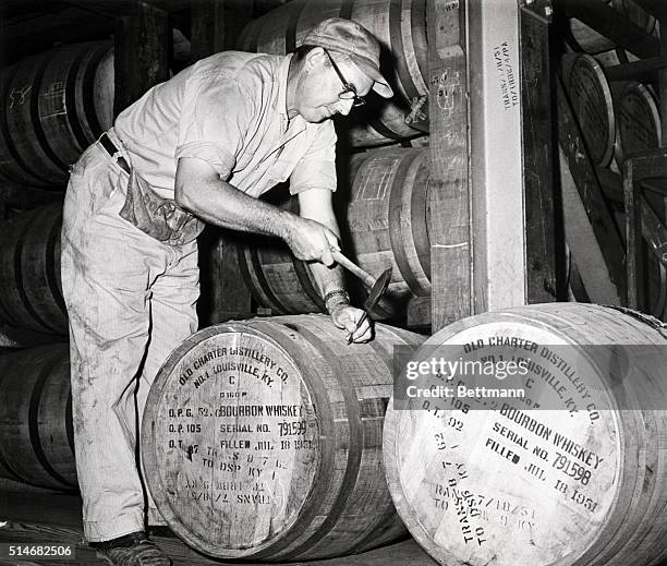 Distiller Joseph Wathen plugs a bourbon whiskey barrel in the warehouse of a Louisville, Kentucky, distillery. September 14, 1962.