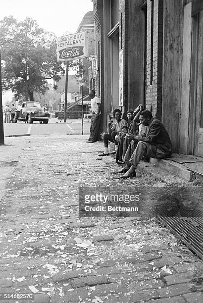 Group of young people sit on sidewalk littered with debris from a bomb blast at the nearby 16th Street Baptist Church which killed four children.
