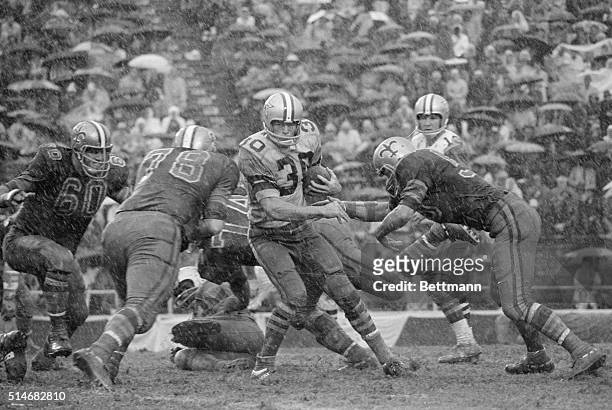 Dallas Cowboy's player Dan Reeves tries to hold on to the ball and run as a downpour turns the field to mud. The New Orleans Saints eventually beat...