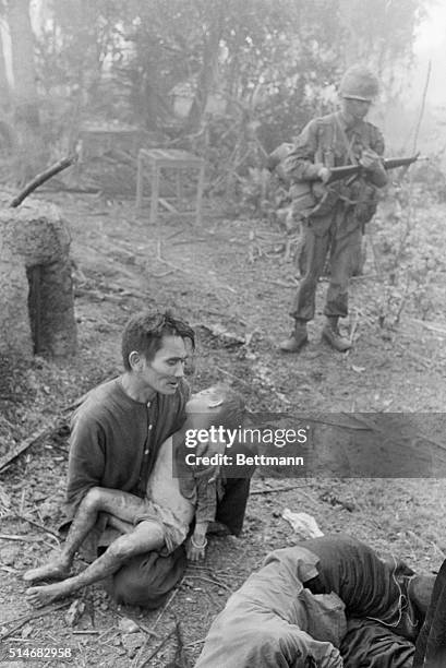 Soldier stands nearby as a Vietnamese father cradles his dead son in Bon Son, Vietnam. The child was killed during fighting between the US First...