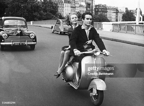 Paris, France: Jean Seberg hitches a ride behind young French actor Phillippe Forquet as they scooter through the street of Paris. Jean will appear...