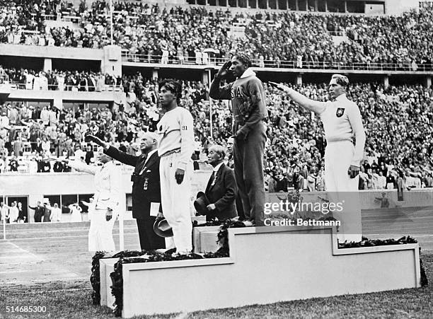 The gold, silver and bronze medal winners in the long jump competition salute from the victory stand at the 1936 Summer Olympics in Berlin. From...