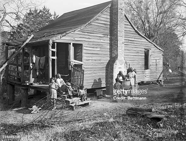 Two African American women wash clothes in the yard of a form slave shack on a Natchez, Mississippi plantation. Their younger children play nearby...