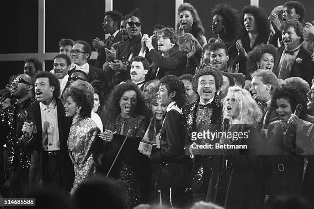 Variety of music and movie stars sing "We Are The World" a song written to benefit famine victims in Ethiopia. Across the front row stands: Stevie...