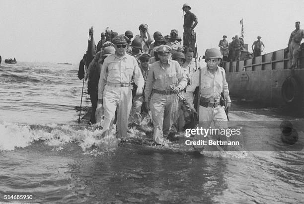 Leyte, P.I.: Gen. Douglas MacArthur and his chief of staff, Lt. Gen. Richard Sutherland wade through knee-deep water from landing craft at the start...