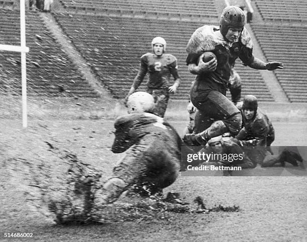 Los Angeles, CA: "Unusual" California weather produced this unusual picture, as Bruin quarterback Bob Waterfield goes down with a muddy splash after...