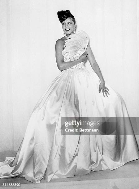 Josephine Baker, American born negro dancer who has been appearing in Paris, models this stunning gown, one of the many she is taking along with her...