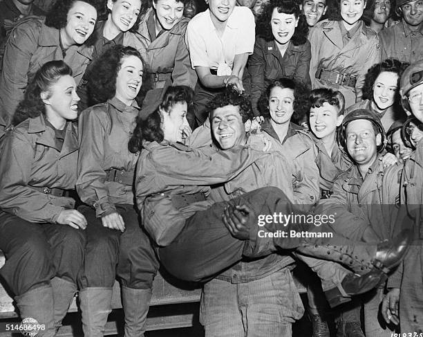 France: Grinning from ear to ear , this G.I. Gets an armful of beauty as USO girls put on their first camp show for the entertainment of Yank troops...