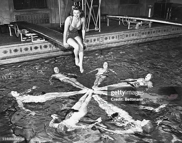 Chicago, IL: The star looks down. Screen star Esther Williams, who knows here way around a swimming pool herself, stays dry as she inspects a star...