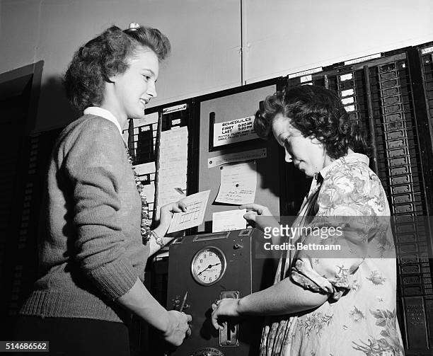 Betty Schmitz and Patricia Donohue punch the time clock before work at Montgomery Ward.