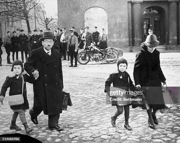 Memel, Germany: A picture which clearly illustrates refugee family walks thru the cobbled streets of the twon as uniformed Nazis in the background...