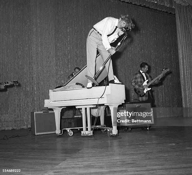 Standing atop a piano, rock 'n' roll singer Jerry Lee Lewis gives an enthusiastic performance at the Cafe de Paris in New York City on June 10, 1958.