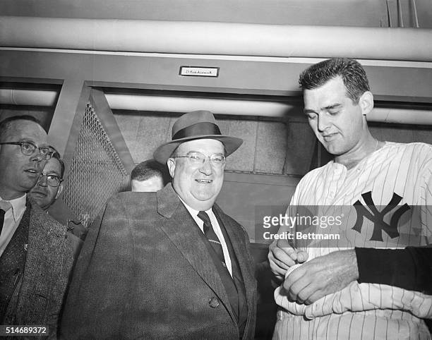 New York Yankees pitcher Don Larsen signs a baseball after becoming the first pitcher to pitch a perfect World Series game. Walter O'Malley, the...