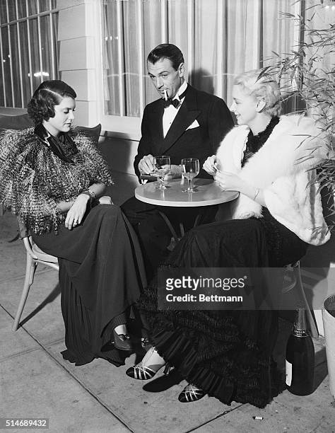 Hollywood, CA: Left to Right- Mrs. Gary Cooper, and Gary Cooper, and Virginia Bruce were among the screen notables who attended the "Preview Opening"...