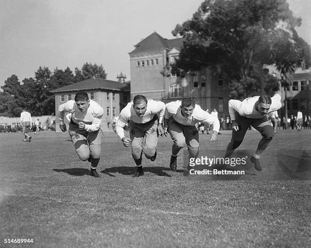 The USC football team rushes towards the camera. From left to right are R. Brown, Ernie Smith, Aaron Rosenberg, and Bob Hall.