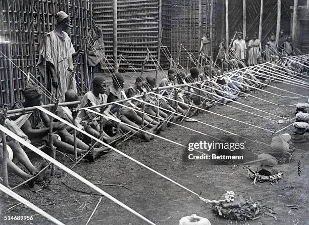 Group of Fumban men weave strips using handlooms.