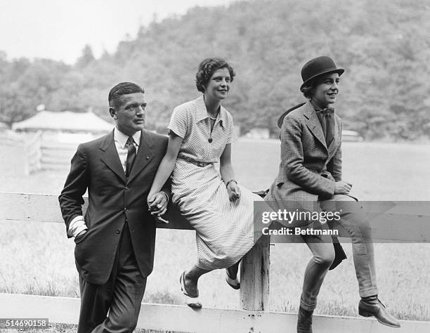 John Bouvier III, father of Jacqueline Bouvier, and Virginia Kernochan hold hands while Janet Lee Bouvier sits nearby. The three watch the first...