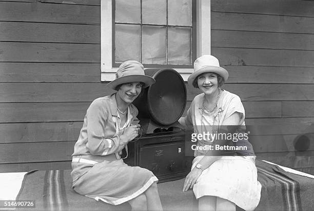 Two flapper girls listening to radio loud speaker. 1932 photograph.