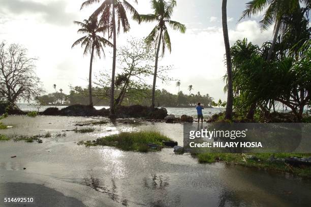 In this photo taken on March 9 a resident walks through tidal water in Majuro Atoll, in the Marshall Islands. - Residents in low-lying areas of the...
