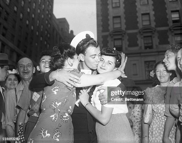 British sailor Ray Bradley celebrates V-J Day in New York City with kisses from two American girls.
