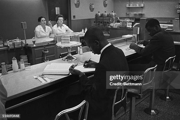 African American students from Saint Augustine College study while participating in a sit-in at a lunch counter reserved for white customers in...