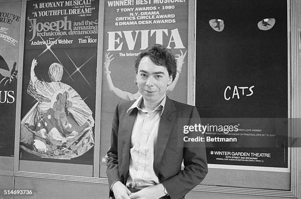 Portrait of composer Andrew Lloyd Webber standing in front of billboards advertising his three musicals Joseph and the Technicolor Dreamcoat, Evita,...