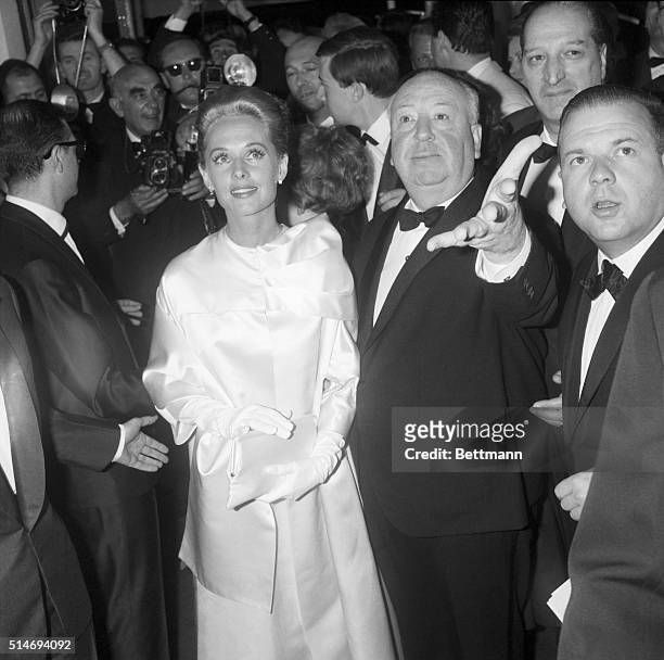 Surrounded by photographers, film director Alfred Hitchcock escorts Tippi Hedren, the star of his new film The Birds, to a screening of the film at...