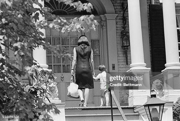 Jackie Kennedy, widow of the late President John F. Kennedy, walks with her son John, Jr. , into their Georgetown home.