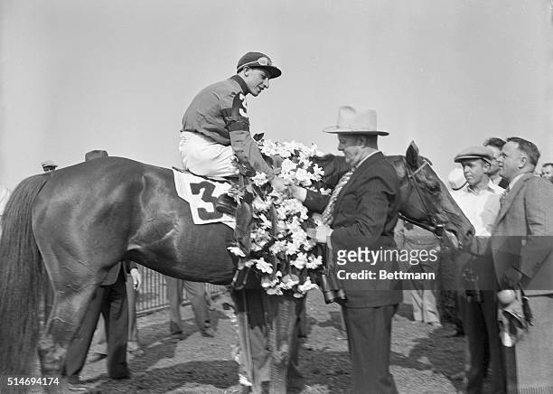 New York: Trainer B.A. Jones shakes hands with jockey Eddie Arcaro after the latter booted "Whirlaway" home in front to win the Belmont, feature race...