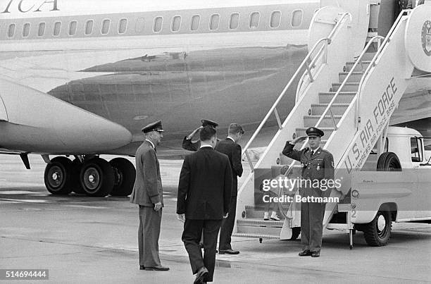 President John F. Kennedy watches his young son John, Jr., climbing up the steps of a plane at Andrews Air Force Base. The president left to a tour...