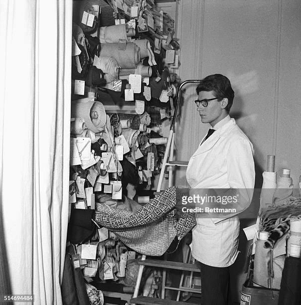 Top French fashion designer Yves Saint Laurent selects fabrics from the bolts in his Paris studio.