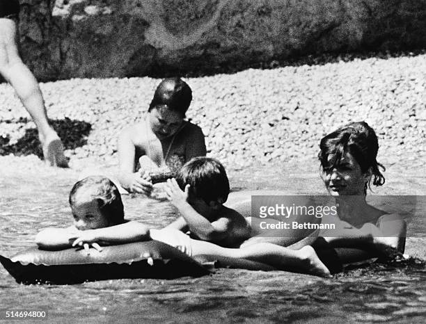 First Lady Jackie Kennedy pushes two floats with her daughter, Caroline, and niece, Anna Christina Radziwill, in Cinca Del Marini. The Kennedys are...