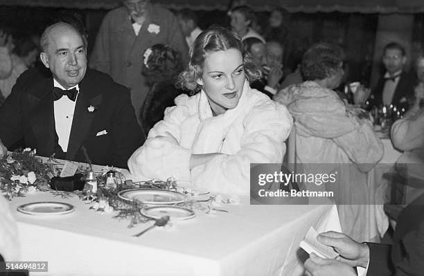 Socialite Doris Duke rests at a table wearing a white fur coat during the Green & White Ball at Palm Beach's Colony Club.