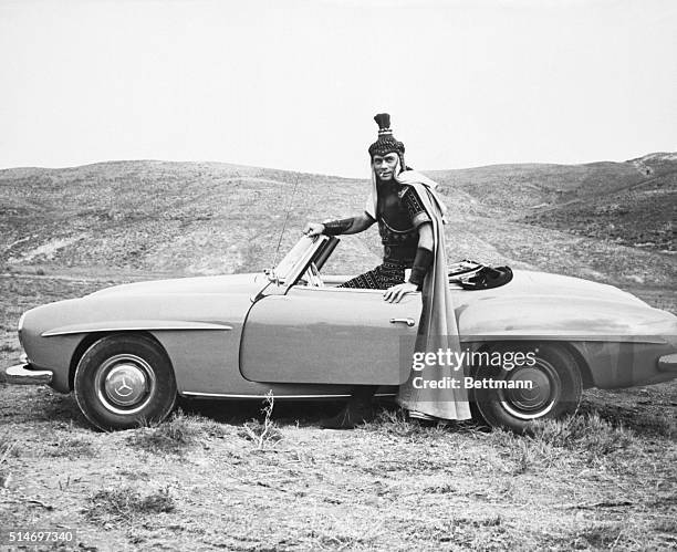 Actor Yul Brynner, in costume for the movie Solomon and Sheba takes a break and goes for a spin in his Mercedes-Benz 190 SL.