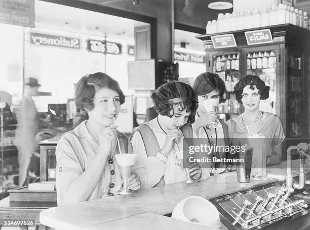 Flappers at a soda fountain drinking milk shakes in 1926.