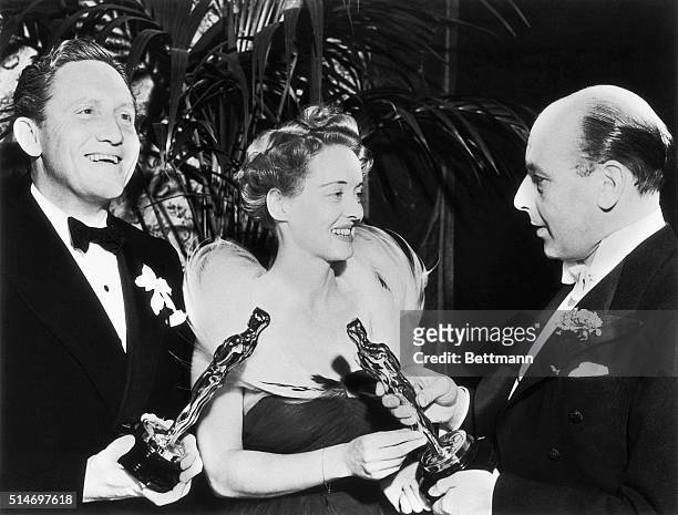 Los Angeles, CA: Cedric Hardwick presents the Academy Awards to a smiling Spencer Tracy, who won for "Boy's Town" and a beaming Bette Davis, who won...